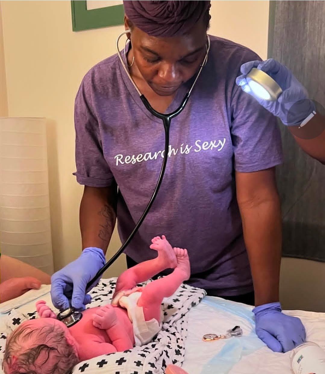 A midwife listening to a newborn with a stethoscope