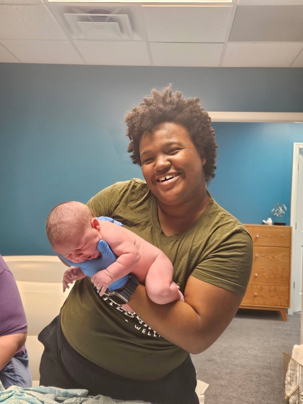 A smiling midwife holding a newborn