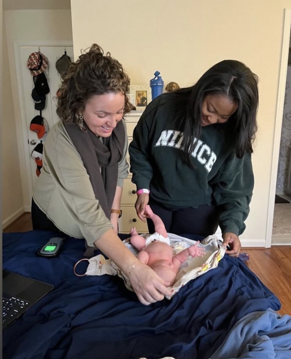 Two midwives examining a newborn together